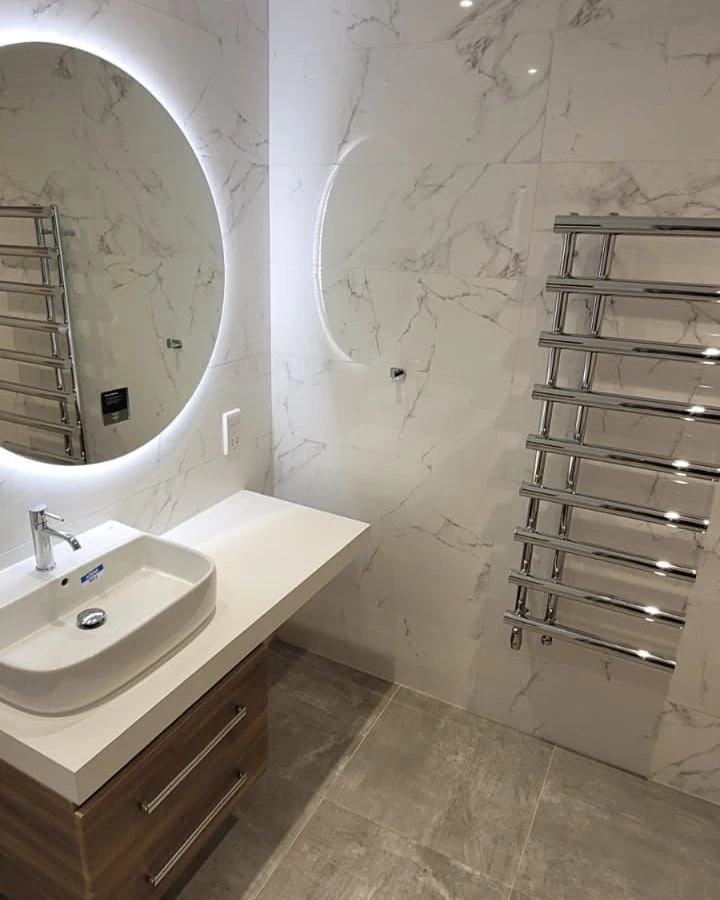 Backlit bathroom mirror and heated towel rail installed